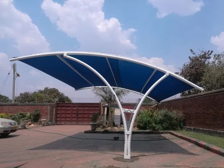 White curved arms with blue shade net over a driveway