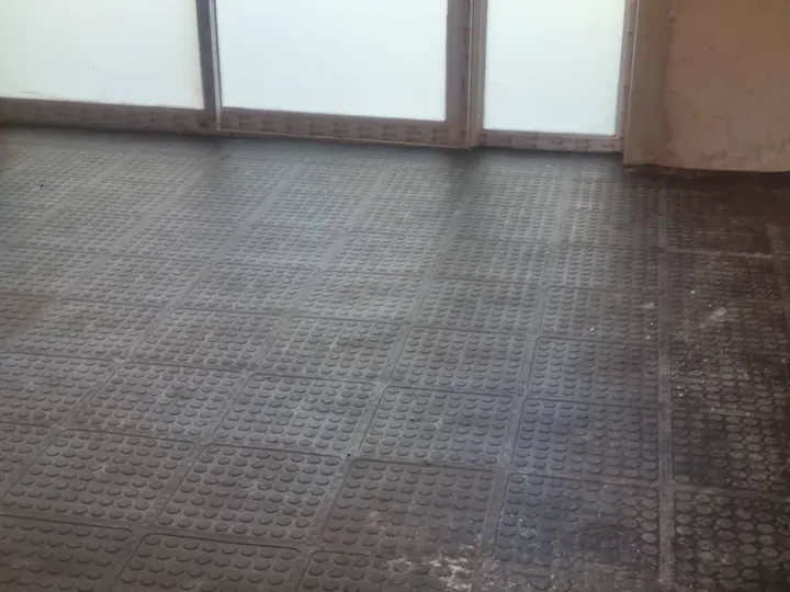 Coin-top tiles laid wall to wall in front of a glazed partition